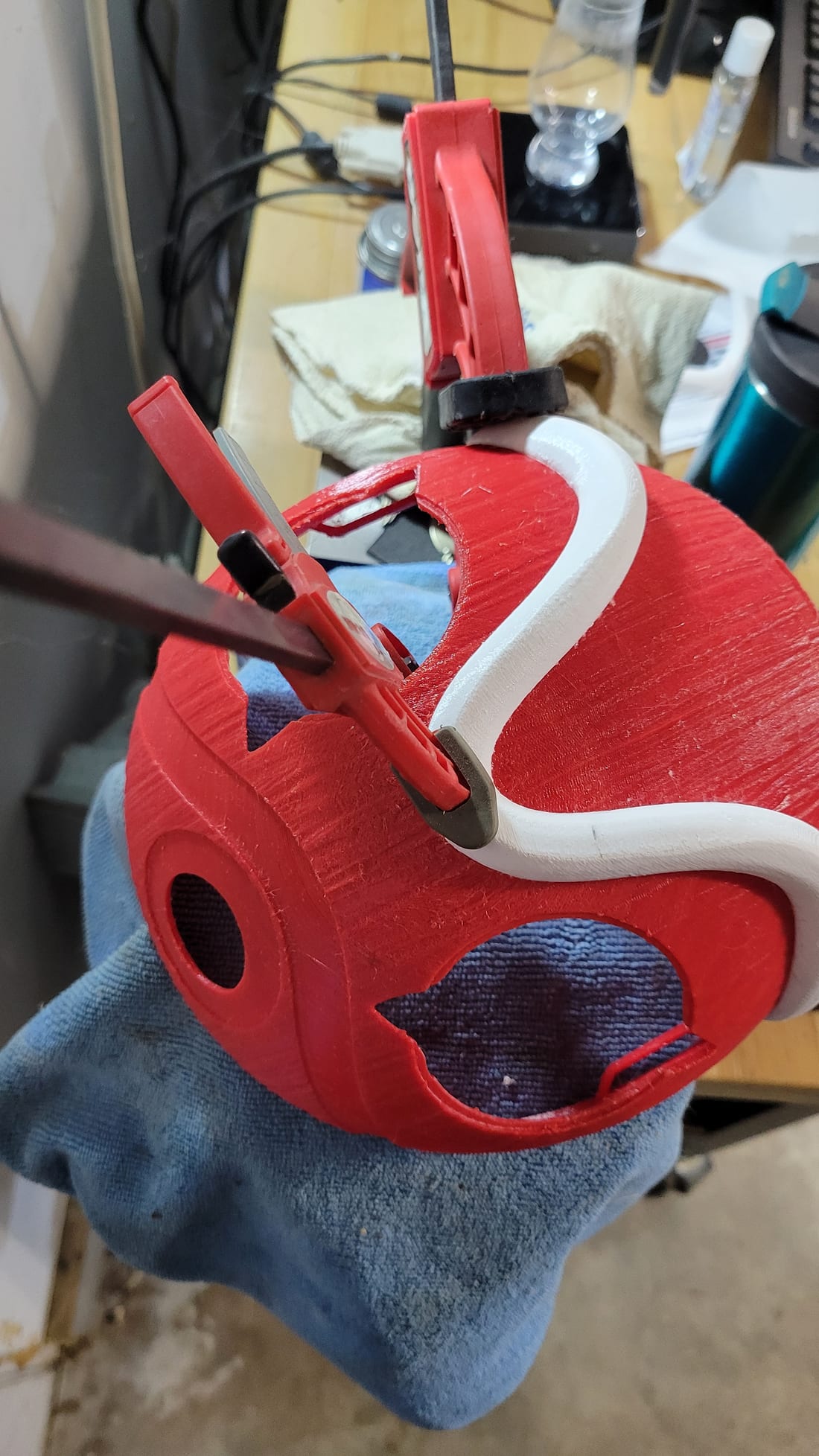 Figure 5 — Welding the white brow band to the mask body: the band clamped in place while the DCM joint sets, the mask resting on a towel. Source: my photo, 2026-10-04.
